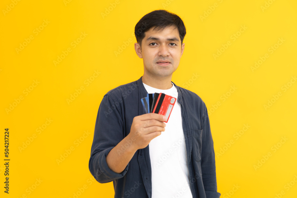 Young man holding credit card with yellow background. Smart boy use credit card for tourism, shopping, e-commerce, internet banking, spending money. Young man holding credit card with yellow background. Smart boy use credit card for tourism, shopping, e-commerce, internet banking, spending money.