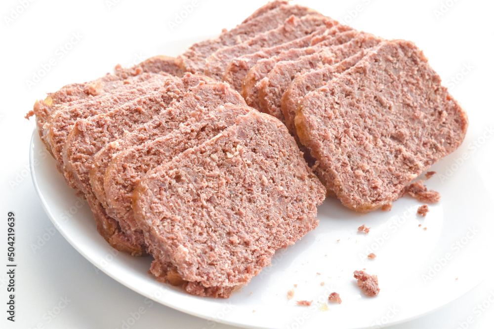 Canned corned beef slices on a white plate. Canned corned beef slices on a white plate.