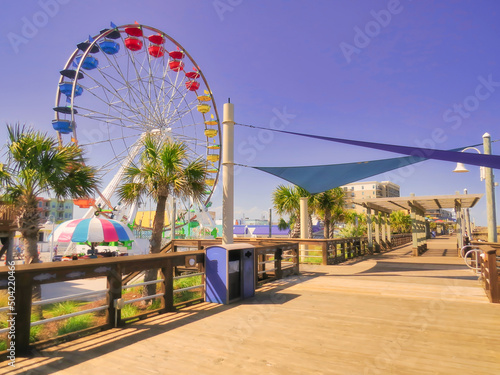 A seaside beach boardwalk with a Ferris wheel under a purple sky. photo