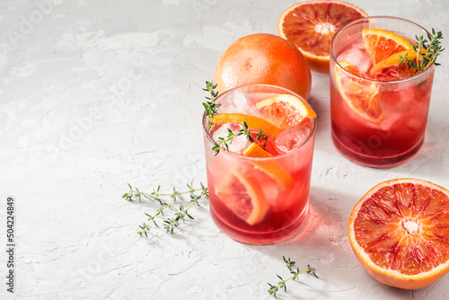 Red cocktail in base of Campari or bitter with  Sicilian red oranges (tarocco) on light gray concrete background, copy space. Aperitif with Americano cocktail. Natural eco  aesthetic, summer light photo