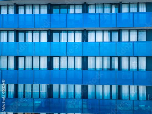 Close-up view from a drone of a modern multi-storey building with many windows and balconies. Multi-storey blue glass building, apartments, hotel