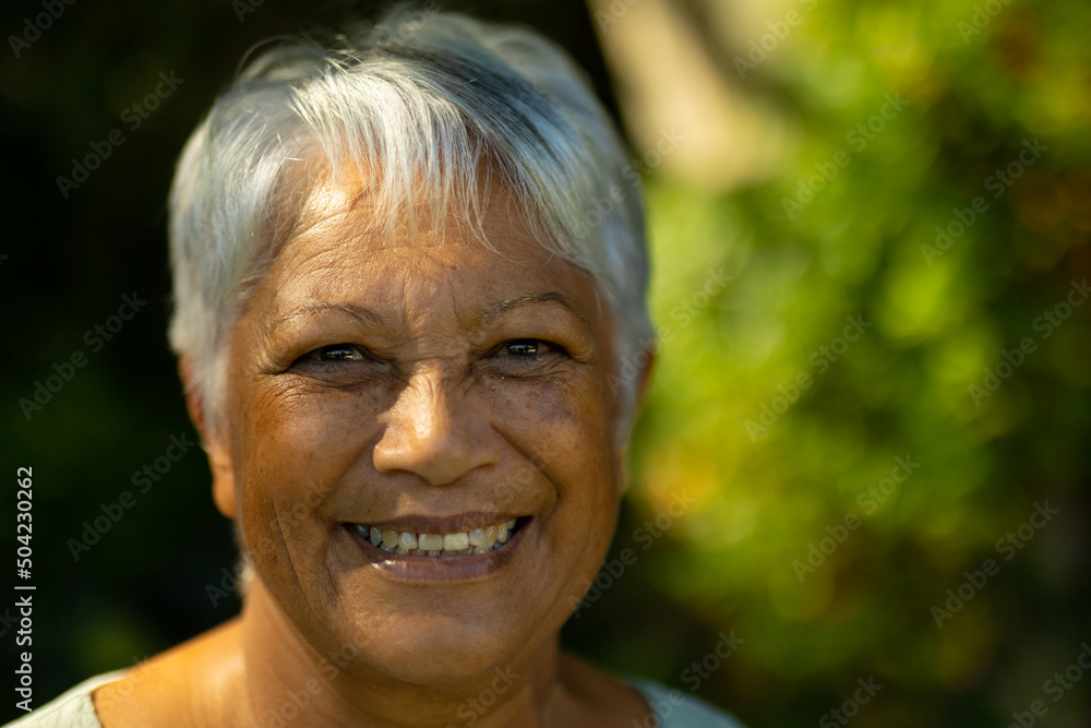Close-up portrait of smiling biracial senior woman with short gray hair in park