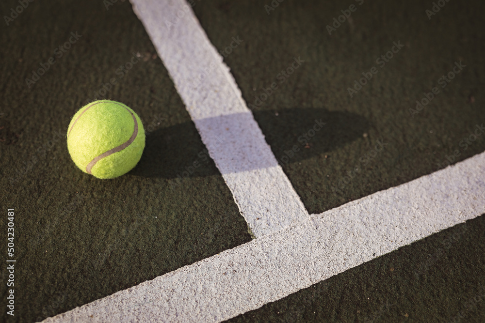 High angle close-up of yellow tennis ball by white lines on tennis court, copy space