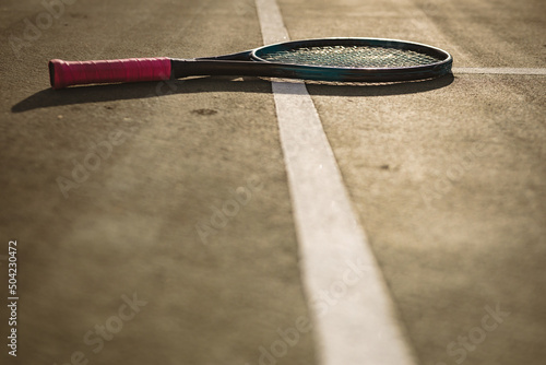 Surface level of tennis racket on white lines at tennis court during sunset, copy space © WavebreakMediaMicro