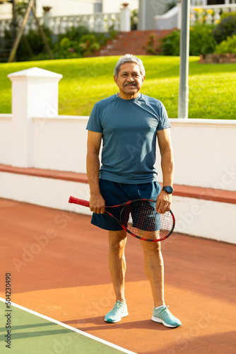 Portrait of confident biracial senior man holding tennis racket while standing in tennis court © WavebreakMediaMicro