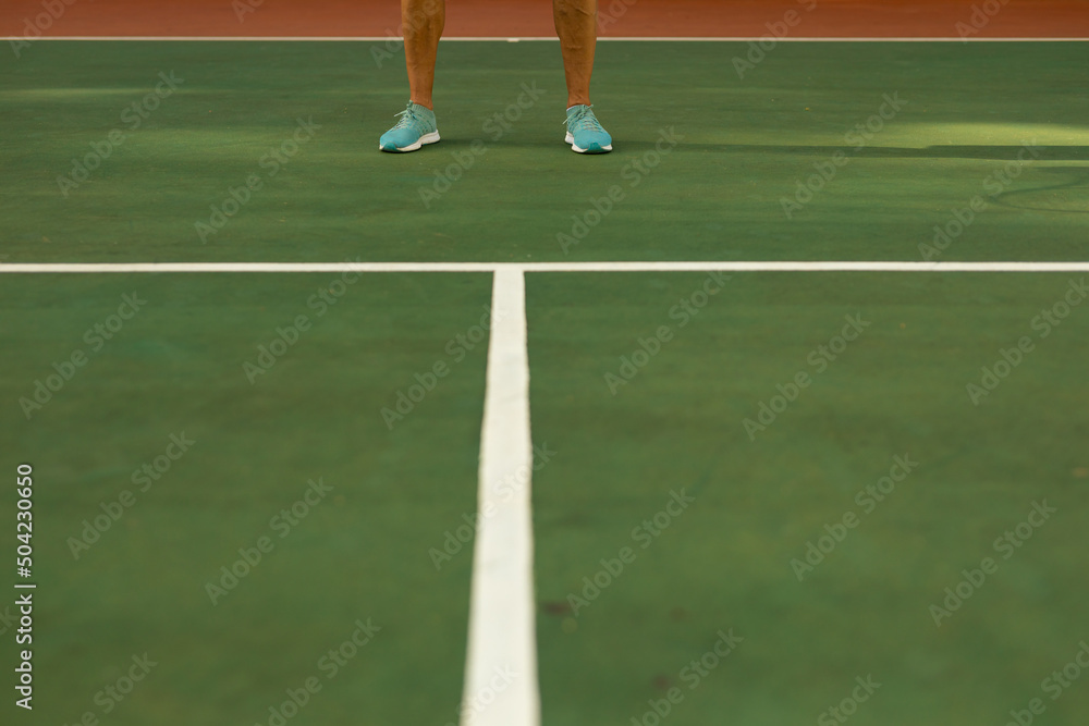 Low section of biracial senior man wearing blue sports shoes standing on tennis court Low section of biracial senior man wearing blue sports shoes standing on tennis court