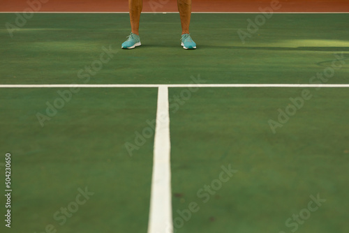 Low section of biracial senior man wearing blue sports shoes standing on tennis court