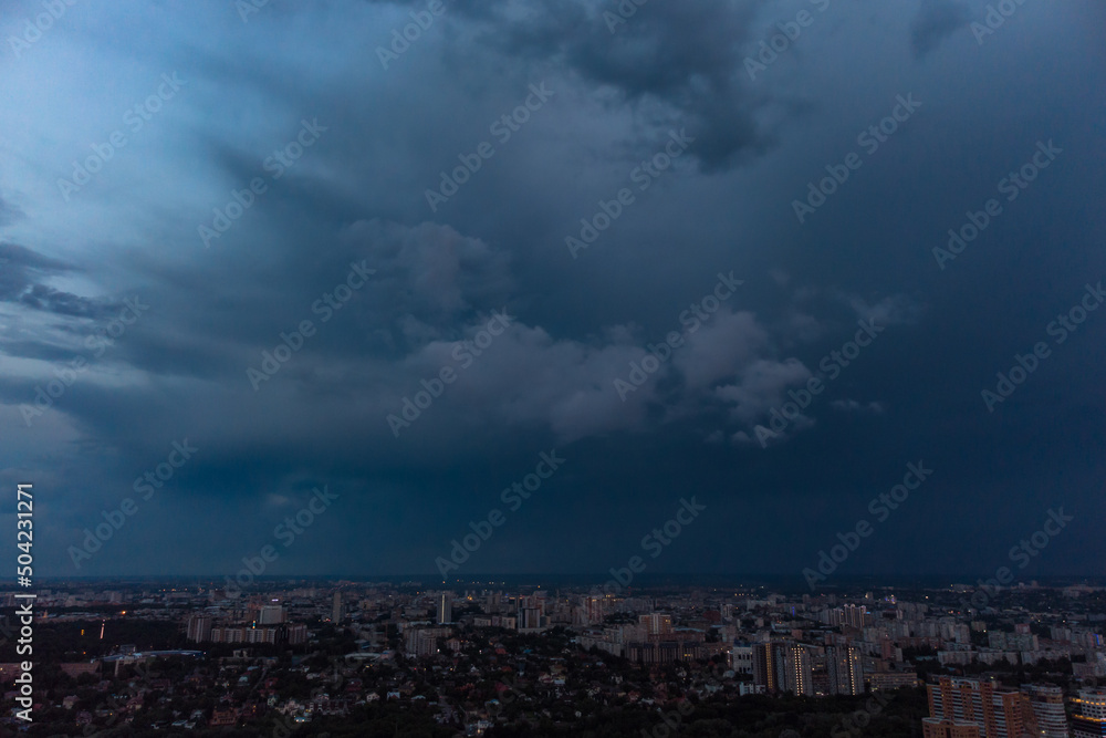 Aerial evening view on city with dramatic heavy sunset sky with clouds. Evening flight above city streets. Kharkiv, Ukraine city center park and residential district