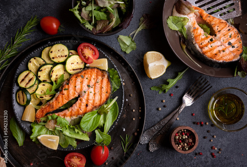 Cooked salmon fish with vegetables on dark background