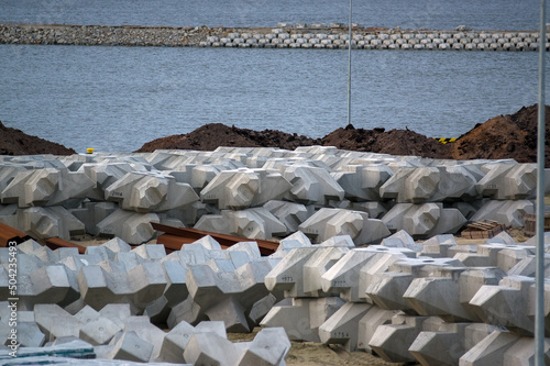 Plac budowy plaża materiały budowlane betonowe bloczki i stalowe pręty zwały piasku. 