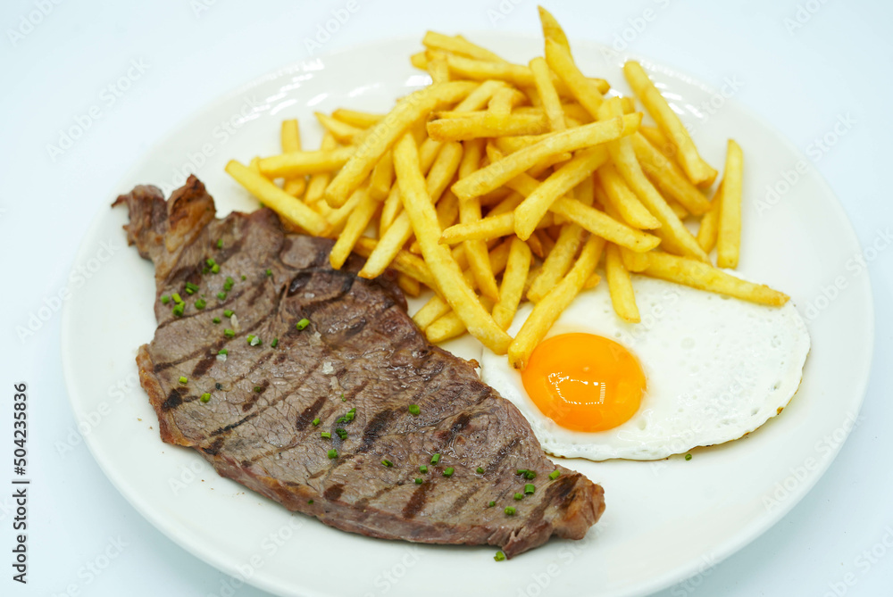 Plato combinado de bistec de ternera con patatas y huevo frito Plato combinado de bistec de ternera con patatas y huevo frito