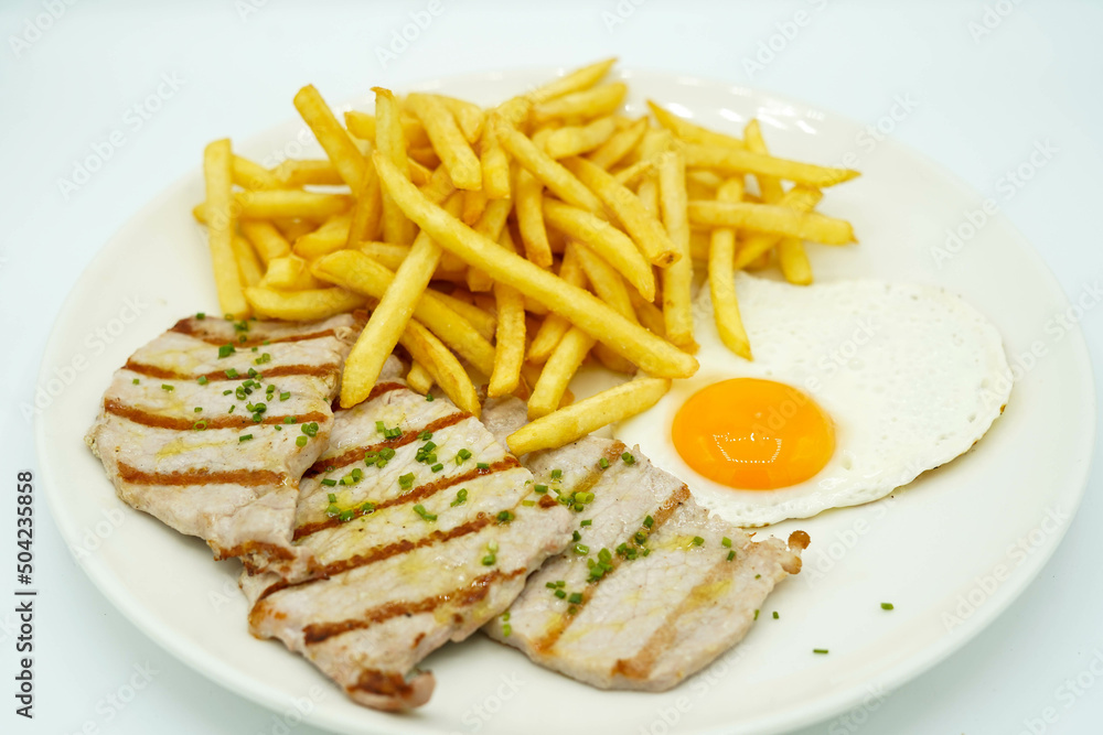 Plato combinado de lomo de cerdo con patatas y huevo frito Plato combinado de lomo de cerdo con patatas y huevo frito
