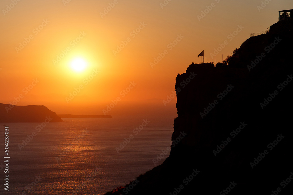Sunset over Aegean sea and rock on Santorini island, Greece
