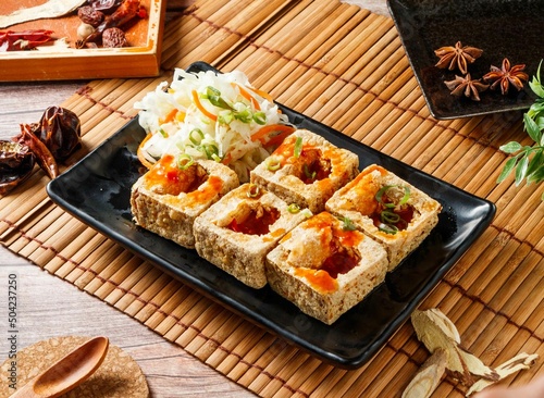 Crispy Fried Stinky Tofu in a black tray with red chili isolated on mat side view of japanese food