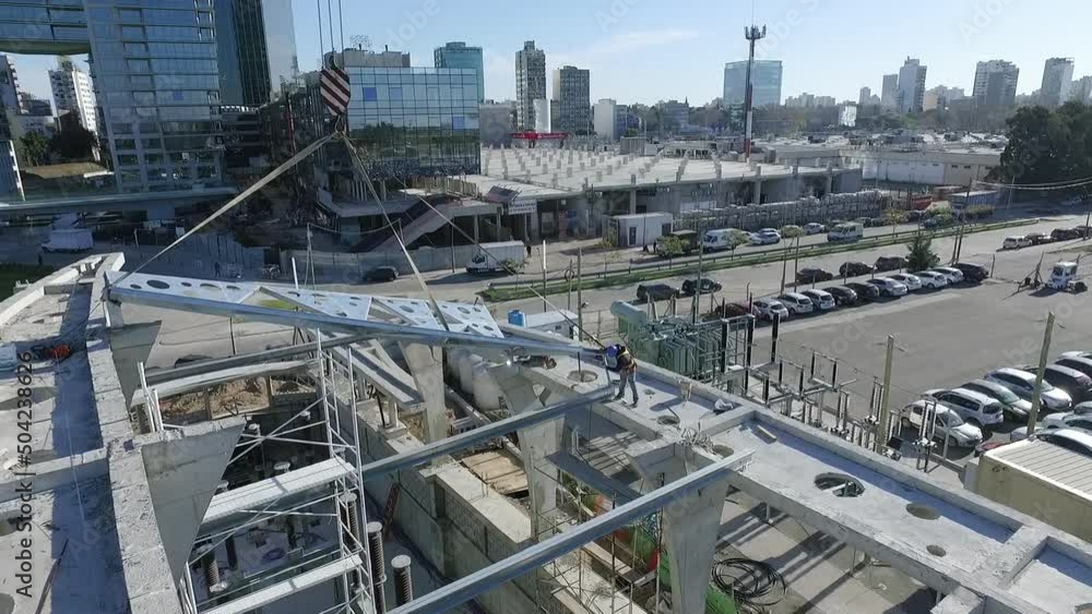 Architecture and design. Under construction. Aerial view of the construction site. View of a huge crane lifting an iron plate. Modern buildings in the background. Architecture and design. Under construction. Aerial view of the construction site. View of a huge crane lifting an iron plate. Modern buildings in the background.