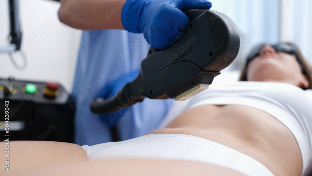 Cosmetologist removing unwanted hair from client body using laser closeup