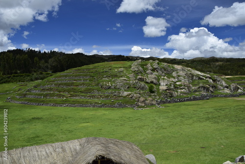 A field with green grass in front of the Inca ruins Saqsaywaman near Cusco. photo