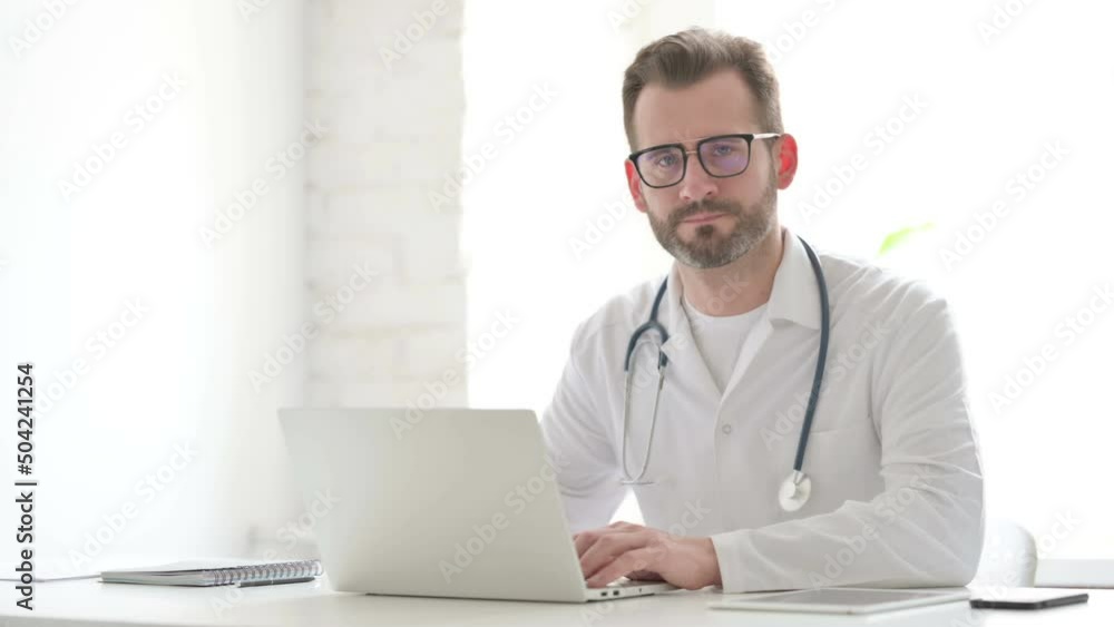 Doctor Shaking Head as No Sign while using Laptop in Office Doctor Shaking Head as No Sign while using Laptop in Office