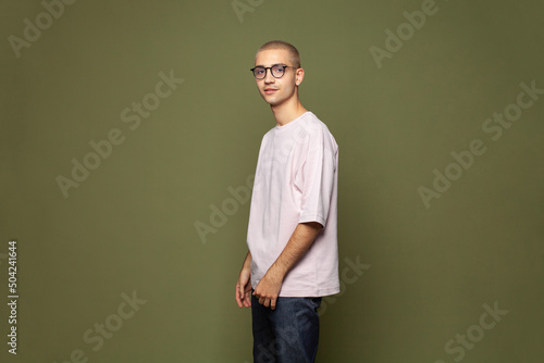 Young cute man standing on green background with copy space photo