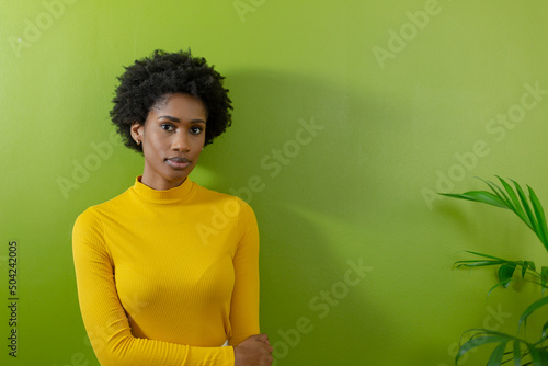 Portrait of african american female advisor standing with serious expression against green wall