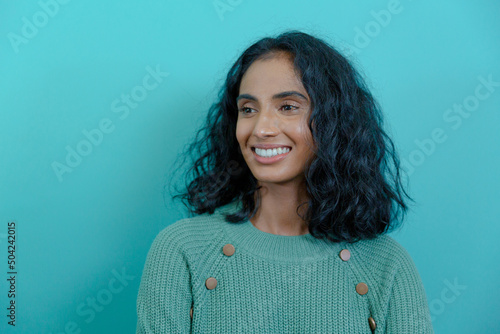 Smiling young biracial female advisor with black hair looking away against blue wall