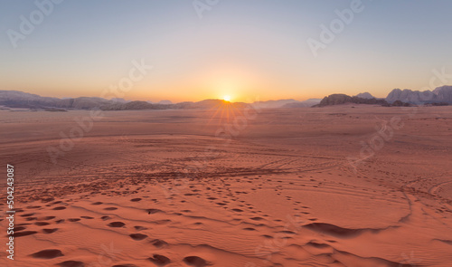 Panoramic view overlooking the red sand desert and Bedouin camp as seen with a cloudy golden sunset in Wadi Rum, Jordan