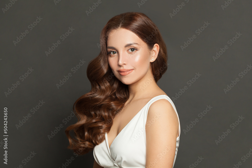 Naklejka premium Cute young model woman with long perfect curly hair and makeup. Beautiful female face with wavy hair on black background portrait