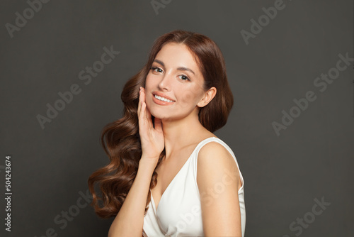 Portrait of beautiful attractive fashion model with long shiny wavy brown hair smiling on black background