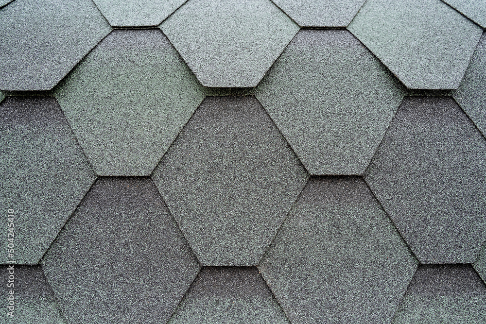 Roofing material on the roof close-up, tiles are the shape of a diamond, the texture of the material is covered with resin, bitumen with sand spraying of the protection layer. Roofing material on the roof close-up, tiles are the shape of a diamond, the texture of the material is covered with resin, bitumen with sand spraying of the protection layer.