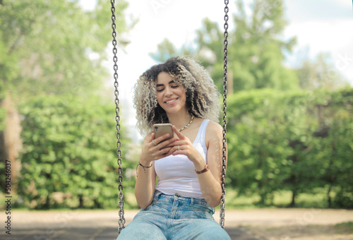 young woman on a swing with a smartphone