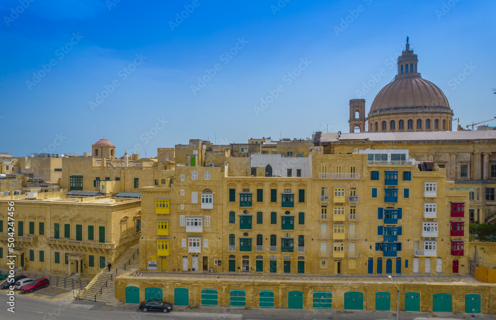 Aerial view of Basilica Lady of Mount Carmel church, St. Paul's Cathedral in the old town of Valetta, Malta. Colorful balconies of Malta capital from above on a sunny day