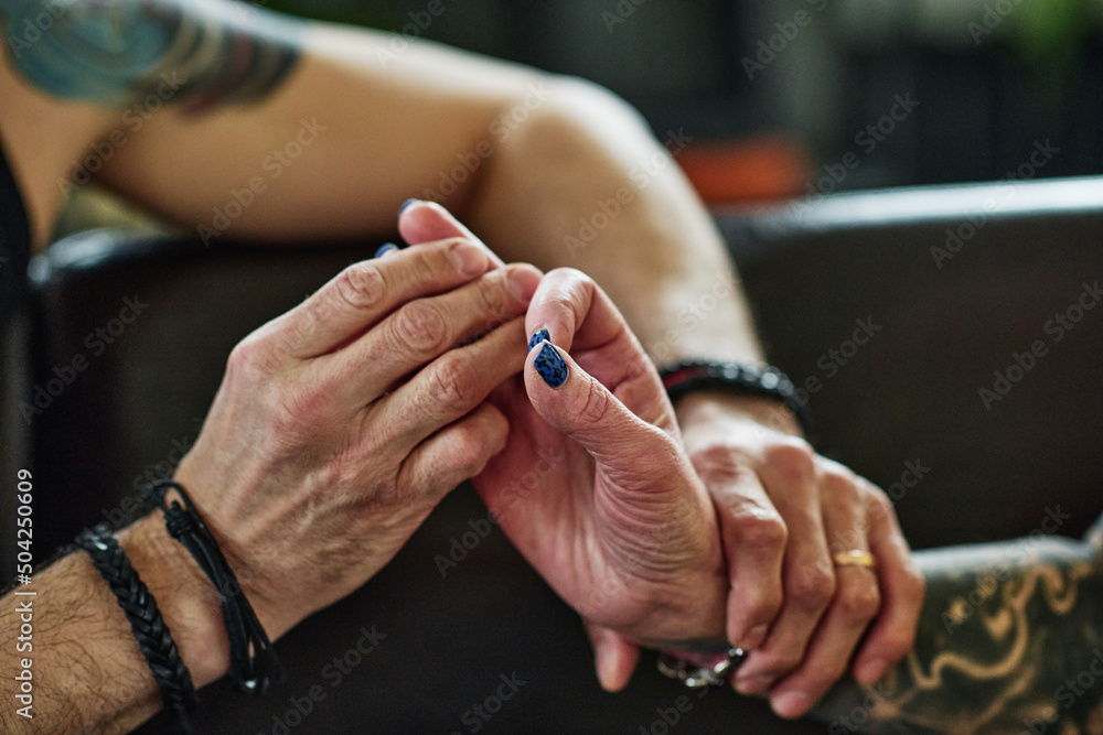 Horizontal close-up shot of unrecognizable man in love holding hand of his tattooed mature wife
