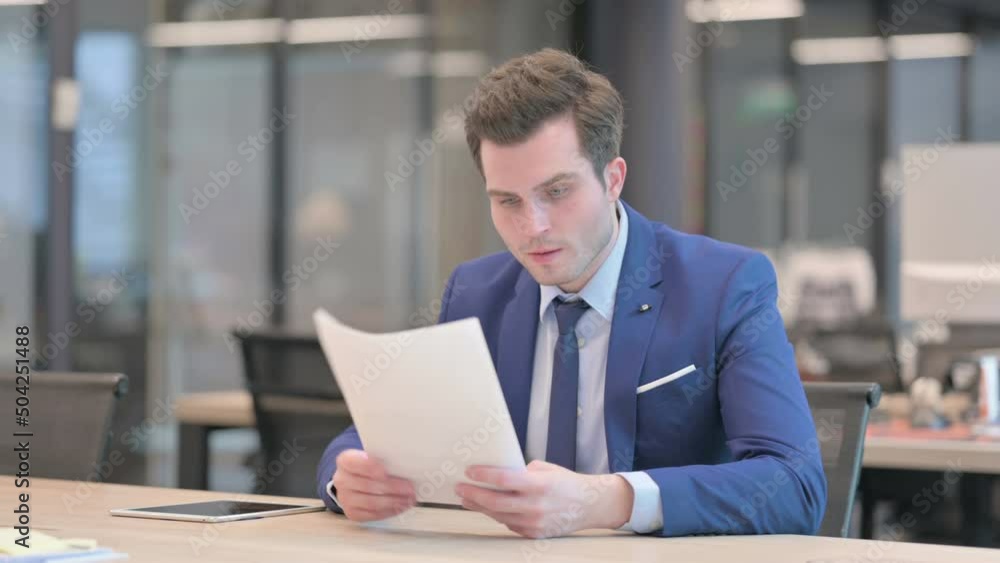 Businessman Upset while Reading Documents in Office Businessman Upset while Reading Documents in Office
