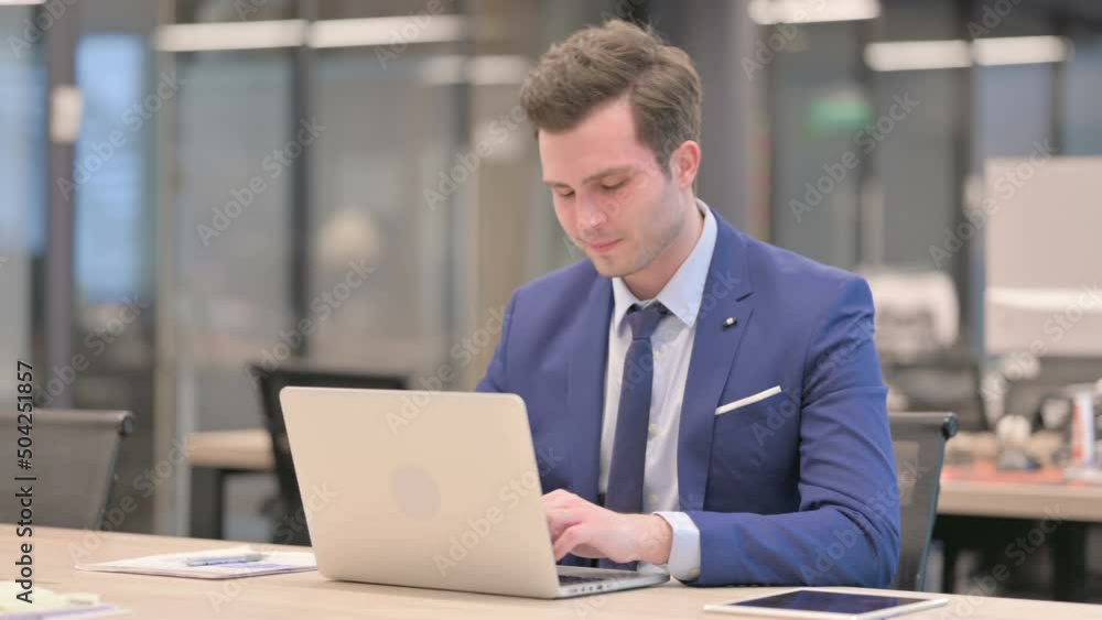 Businessman having Neck Pain while using Laptop in Office Businessman having Neck Pain while using Laptop in Office