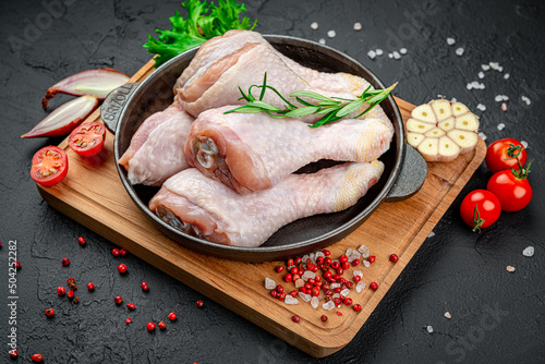 Fresh chicken drumsticks, legs with ingredients for cooking in a frying pan.