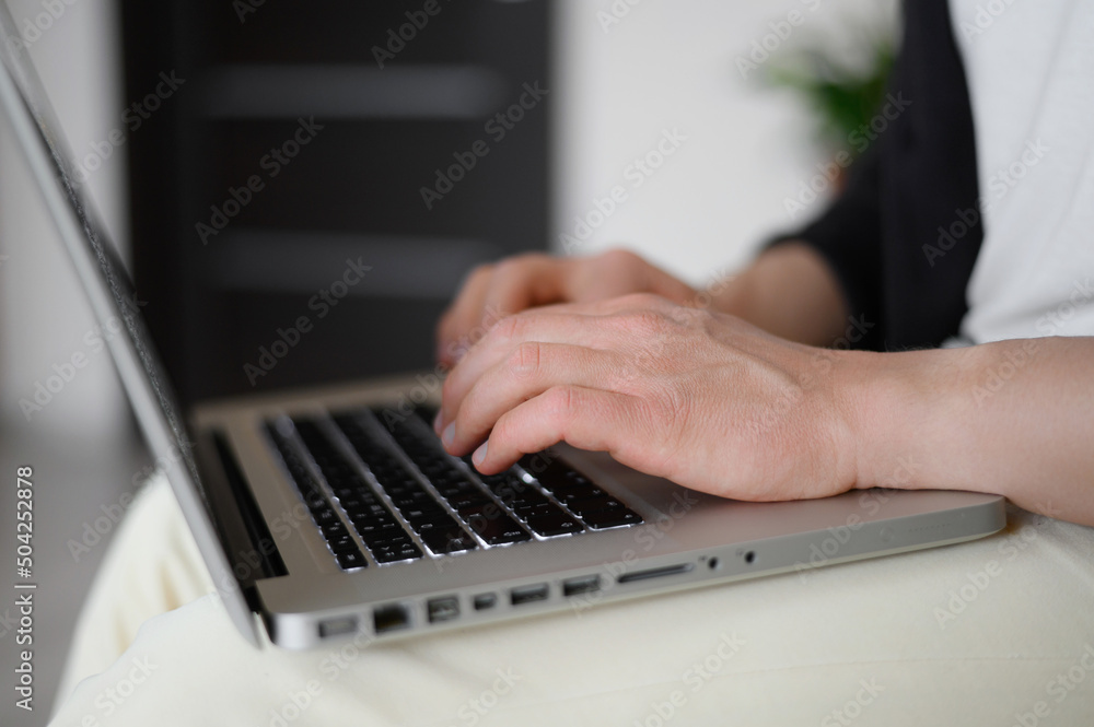 Close-up of male hands typing on a laptop keyboard. The concept of remote work, business investment. Close-up of male hands typing on a laptop keyboard. The concept of remote work, business investment.