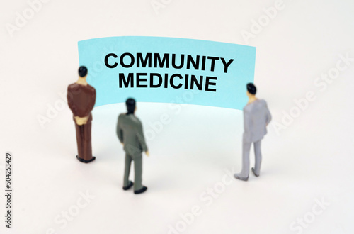 Miniature figures of people stand in front of a blue sign with the inscription - Community Medicine