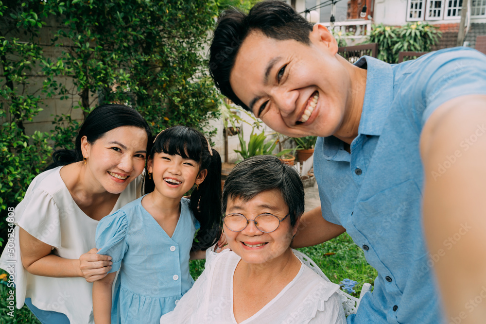 Group of multi-generational Asian family taking a selfie photo together in backyard garden and smiling with happiness. Family spending time and love concept Group of multi-generational Asian family taking a selfie photo together in backyard garden and smiling with happiness. Family spending time and love concept