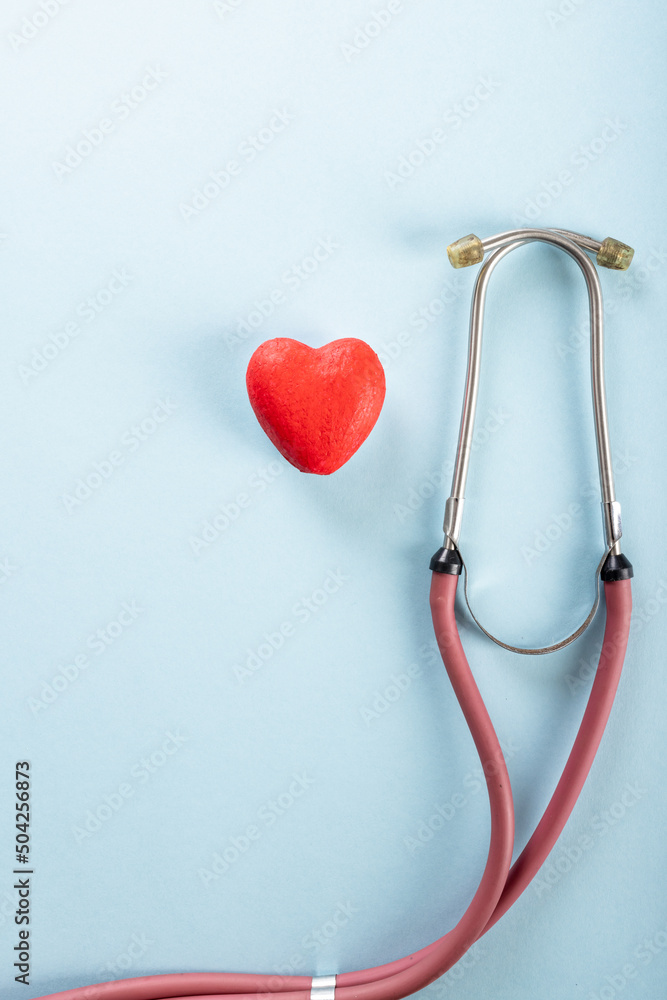 Overhead view of stethoscope with red heart shape against blue background, copy space Overhead view of stethoscope with red heart shape against blue background, copy space