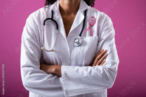 Midsection of african american mid adult woman with stethoscope and breast cancer awareness ribbon