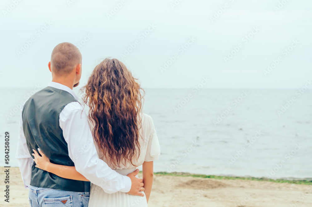 man and woman standing on the shore and looking at the sea