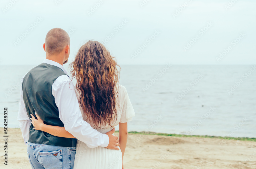 man and woman standing on the shore and looking at the sea man and woman standing on the shore and looking at the sea