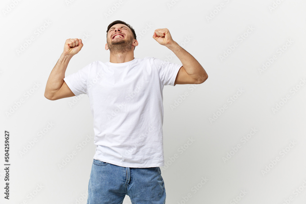 Suffering irritated angry tanned handsome man in basic t-shirt clenches fists close eyes posing isolated on over white studio background. Copy space Banner Mockup. People emotions Lifestyle concept Suffering irritated angry tanned handsome man in basic t-shirt clenches fists close eyes posing isolated on over white studio background. Copy space Banner Mockup. People emotions Lifestyle concept