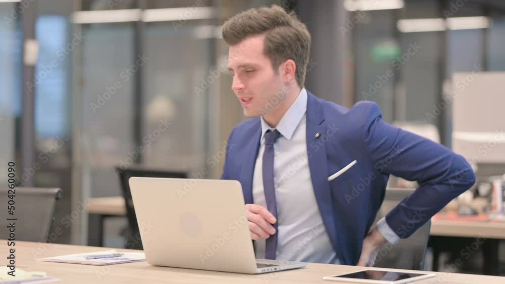 Businessman having Back Pain while using Laptop in Office Businessman having Back Pain while using Laptop in Office