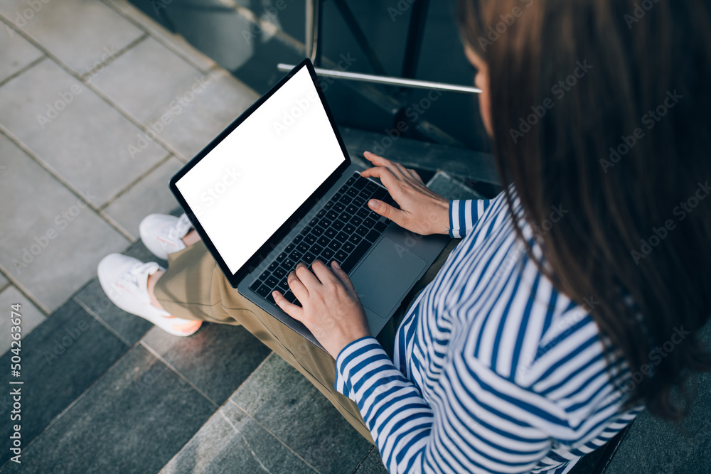 Young woman freelancer working online using her laptop, sitting on stairs. Young woman freelancer working online using her laptop, sitting on stairs.