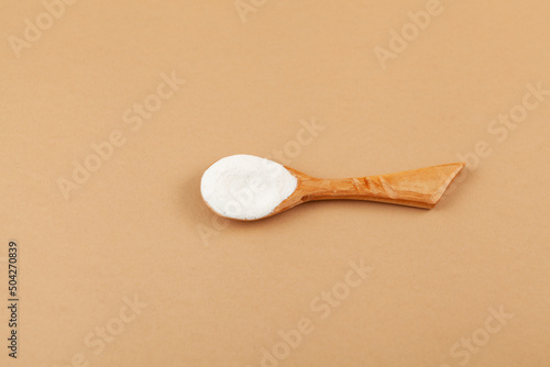 Salep flour in wooden spoon. Also spelled sahlep or sahlab. Salep flour is consumed in beverages and desserts. Beige background, selective focus, copy space photo