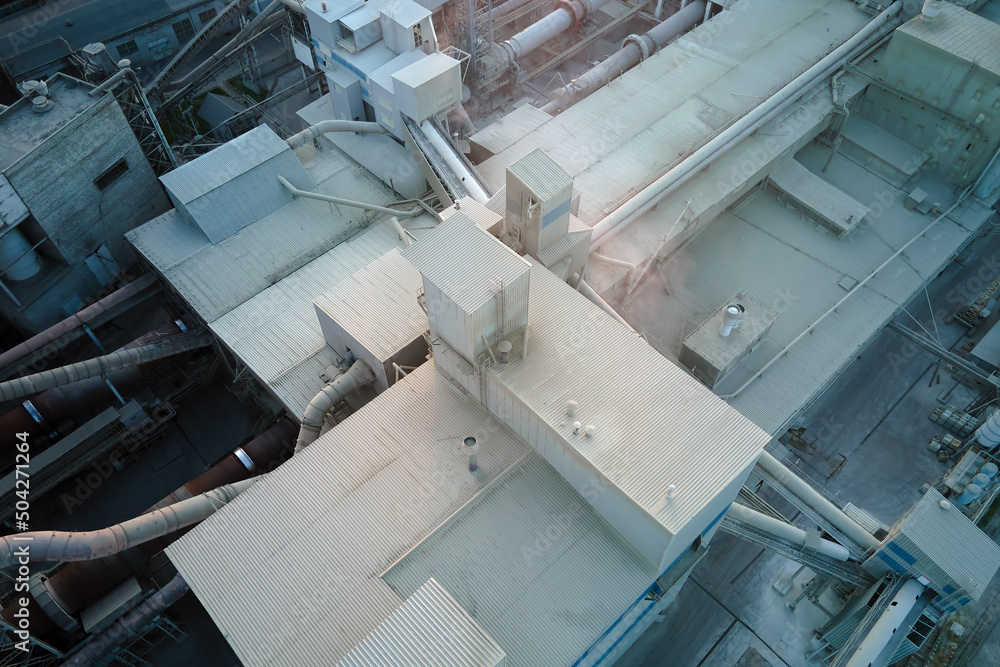 Cement plant with high factory structure and tower cranes at industrial production area. Manufacture, global industry and air pollution concept Cement plant with high factory structure and tower cranes at industrial production area. Manufacture, global industry and air pollution concept