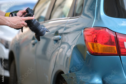 Insurance worker taking photo on camera of dented fender on street side for emergency service after car accident. Road safety and insurance concept