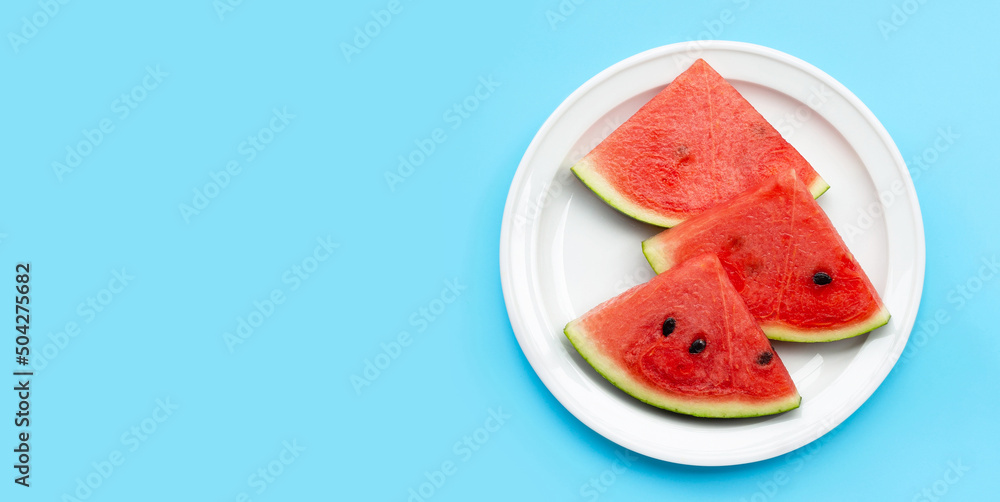 Watermelon slices in white plate on blue background.