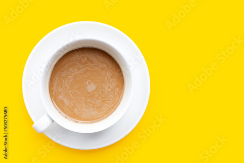 Cup of coffee on yellow background. Top view